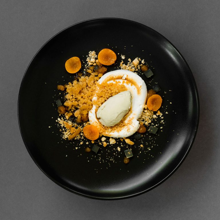 Schwarzer Teller mit Kamilleneis auf Zitronen-Meringue mit Mandelstreuseln, Mirabellen-Granité, Kamillentee-Würfel und Mirabellengel