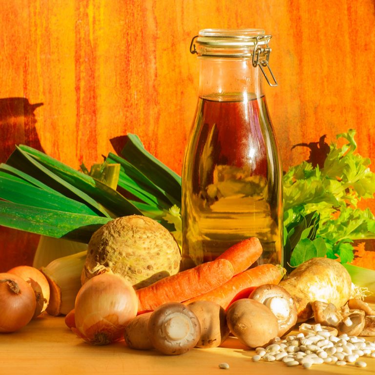 Eine Flasche selbstgemachte Gemüsebrühe, umgeben von Zutaten