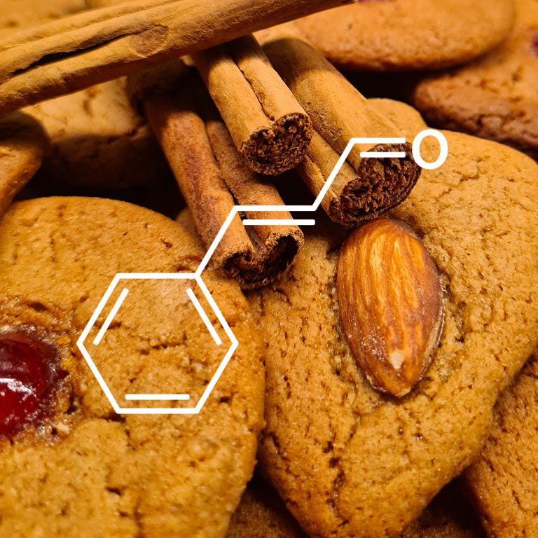 Strukturformel von Zimtaldehyd. Lebkuchen und Zimtstangen im Hintergrund