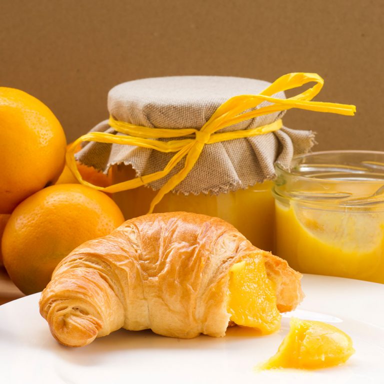 Ein Teller mit Croissant und Bergamot Curd (Bergamotten-Creme), mit Bergamotten (Citrus bergamia) im Hintergrund