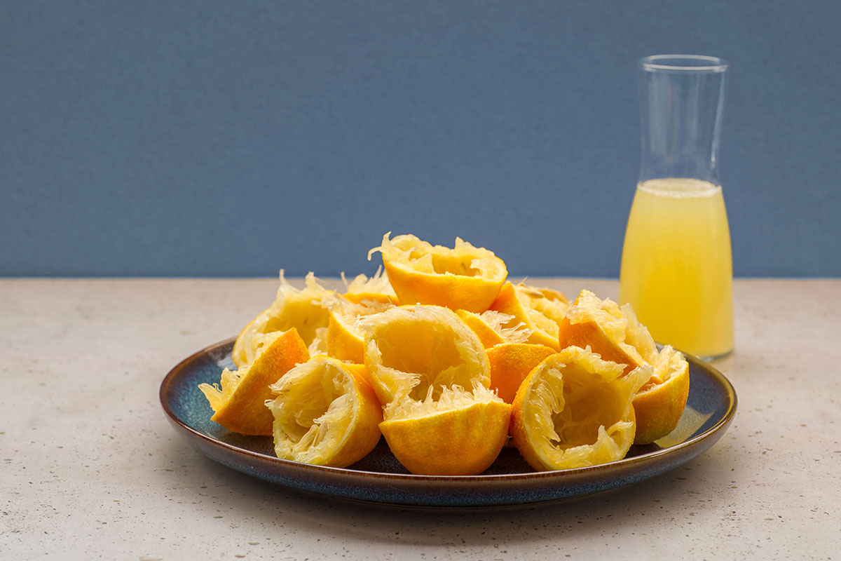 Herstellung von Bergamot Curd. Teller mit ausgepressten Bergamottenschalen und einer Karaffe mit Bergamottensaft.