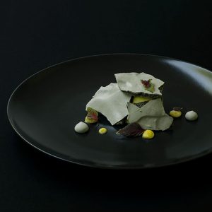Teller mit Bergamotteneis bedeckt von Lakritzbaiser-Platten mit bergamot Curd und roten Shiso-Blättern.