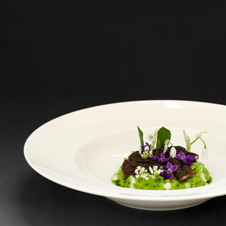 Teller mit Bärlauchspätzle, Bergkäse, Morcheln und Bärlauchöl. Garniert mit Bärlauchblättern und Veilchen, Bär- und Wunderlauchblüten.