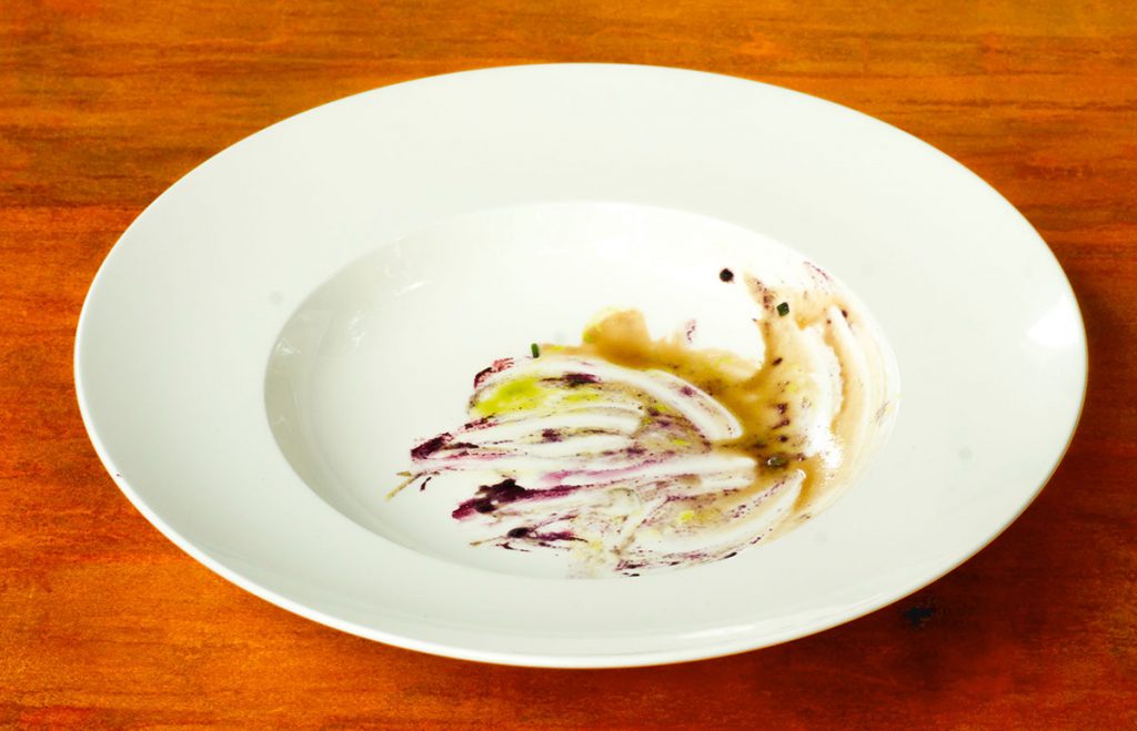 Leerer Teller mit den Überresten von cremigen Pfifferlingen mit confiertem Eigelb und Heidelbeer-Zwiebel-Creme