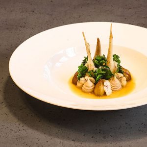 Ein Teller mit glacierten Teltowe Rübchen, glacierten Maronen (Esskastanien), Maronenpüree, rohen Maronenscheiben und blanchierten Fower Sprouts.